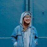woman in blue jacket standing beside walls